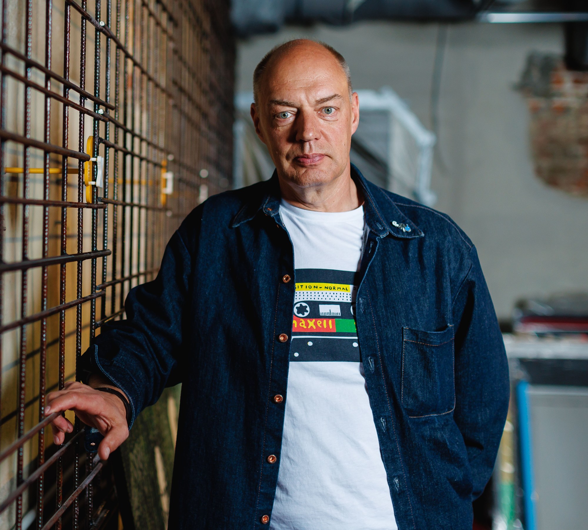 Linnar Viik standing beside a metal grid, wearing a denim jacket.